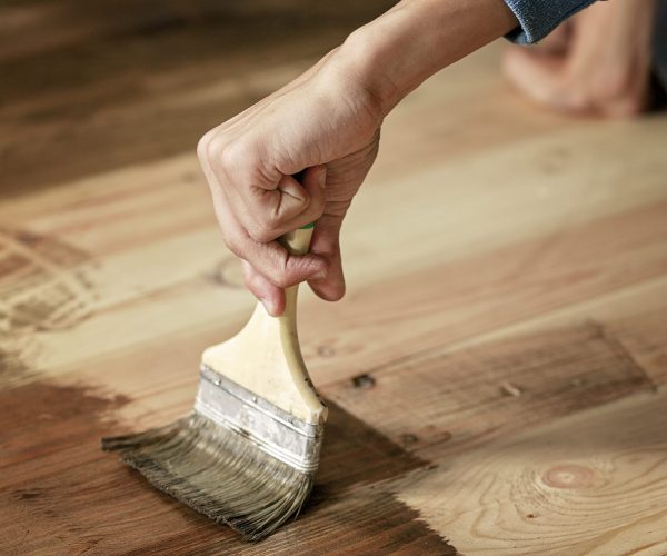 hand-holds-paintbrush-and-paints-the-wood-floor-7J3G8ZU